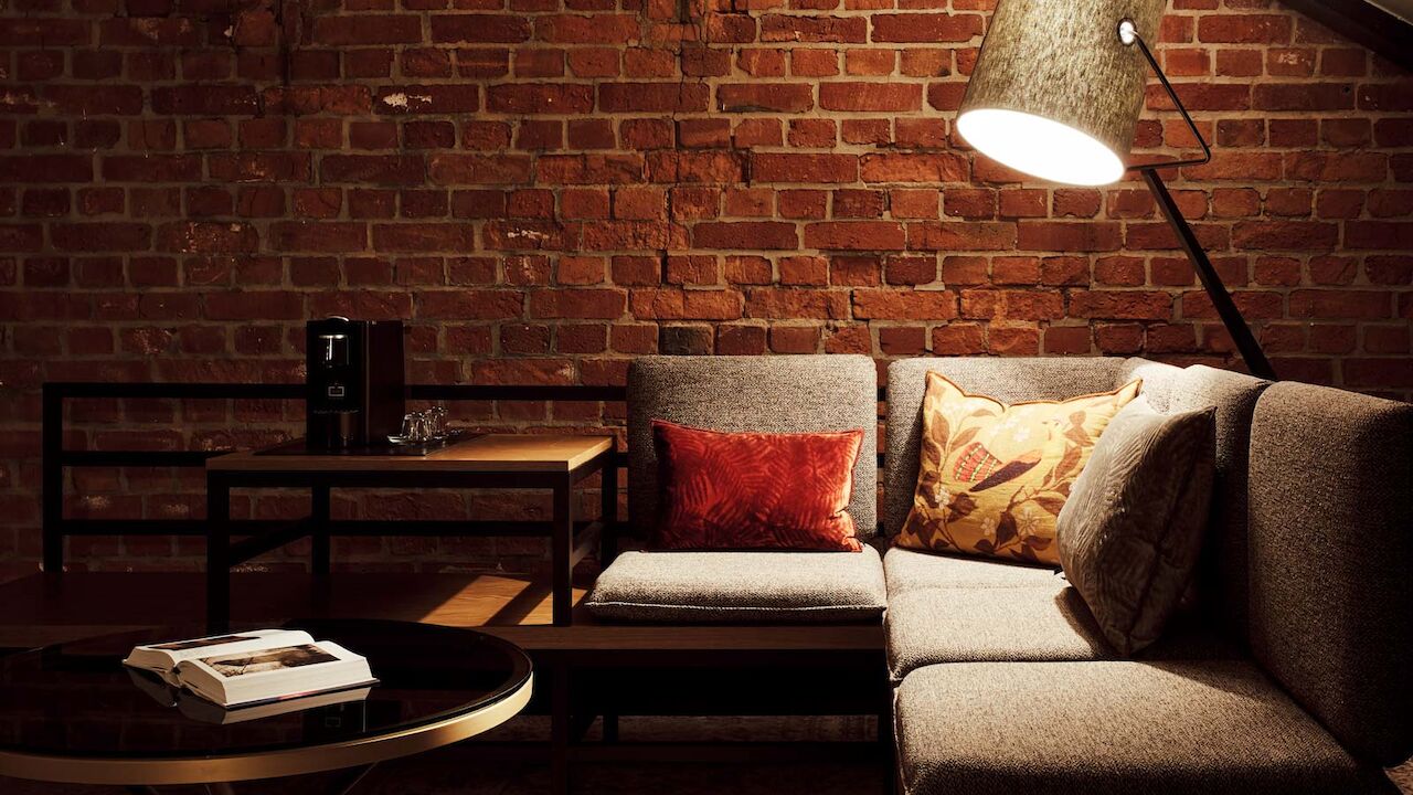 L-Loft mit Sitzbereich, Stehlampe und sichtbarer Backsteinwand