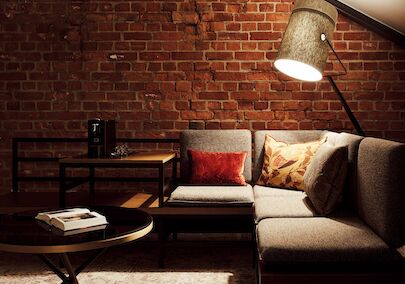 L-Loft mit Sitzbereich, Stehlampe und sichtbarer Backsteinwand