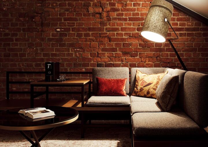 L-Loft mit Sitzbereich, Stehlampe und sichtbarer Backsteinwand