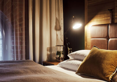 Gemütliches Bett im S-Loft von der Seite mit Nachttischlampe