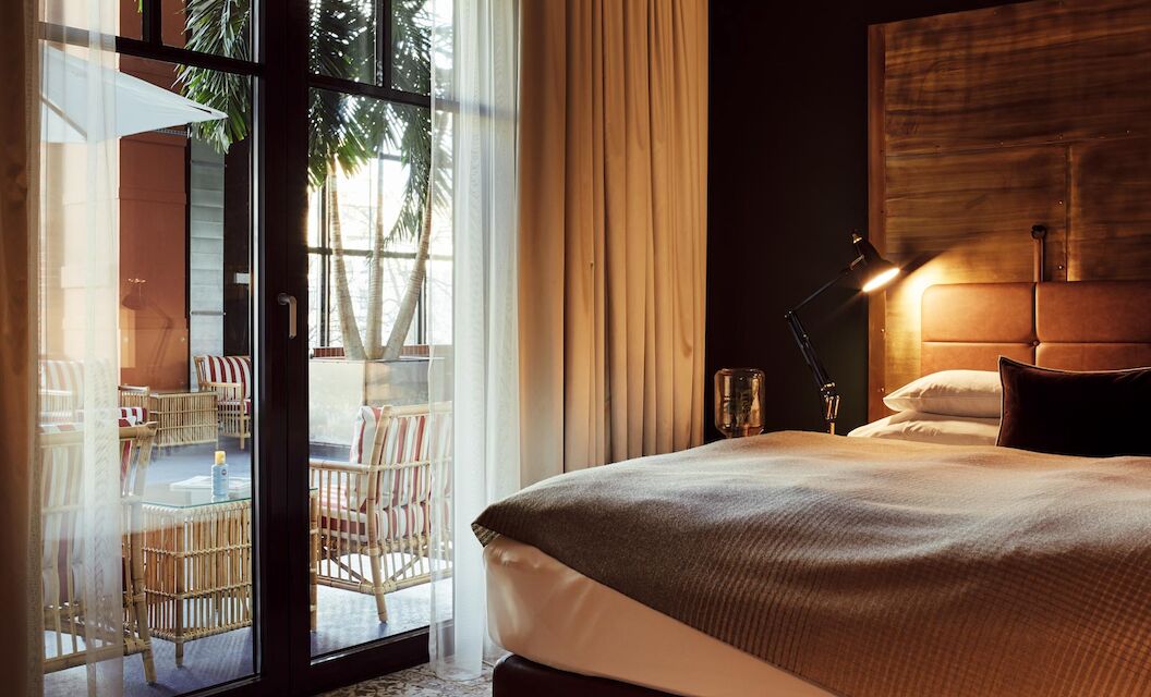Bett und große Fensterfront mit Blick auf das blaue Atrium im S-Loft