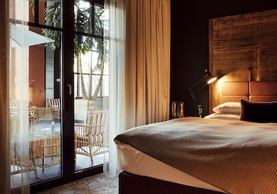Bett und große Fensterfront mit Blick auf das blaue Atrium im S-Loft
