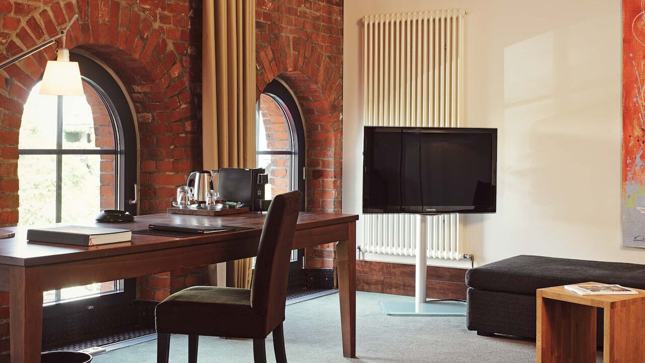 Ein Schreibtisch und TV im XL-Loft mit Backsteinwand