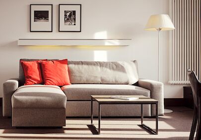Graues Sofa mit Recamiere und roten Kissen, davor ein Beistelltisch