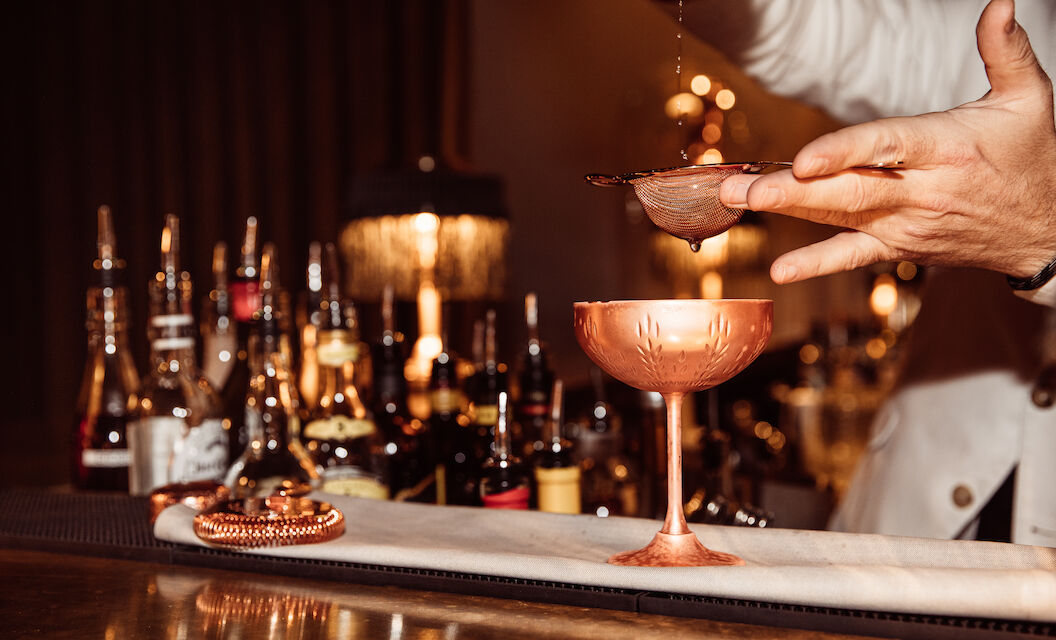Barkeeper gießt Drink durch Strainer in der Mangold Bar im Gastwerk Hotel