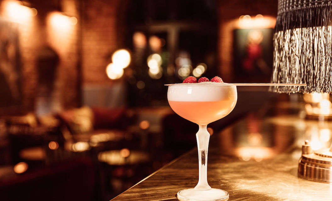 Mangold Bar Cocktail, im Hintergrund Bar-Interieur und Tresen mit Lampe