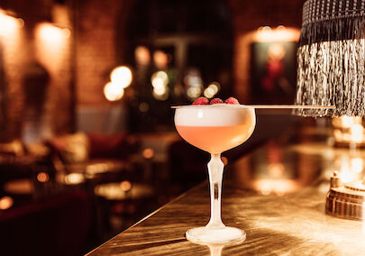 Mangold Bar Cocktail, im Hintergrund Bar-Interieur und Tresen mit Lampe