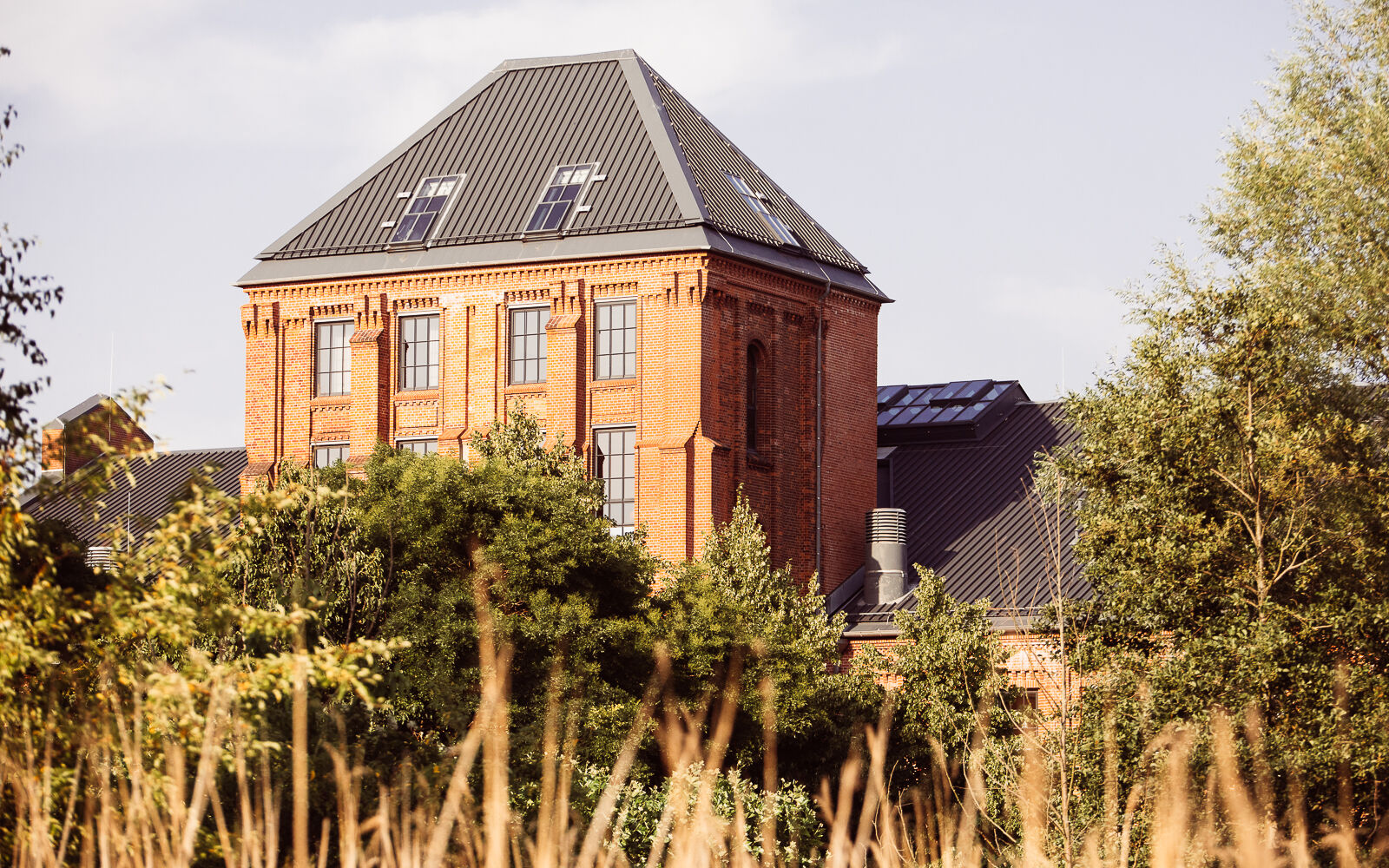 Gastwerk Hotel Gebäudeansicht hinter grünen Baumkronen