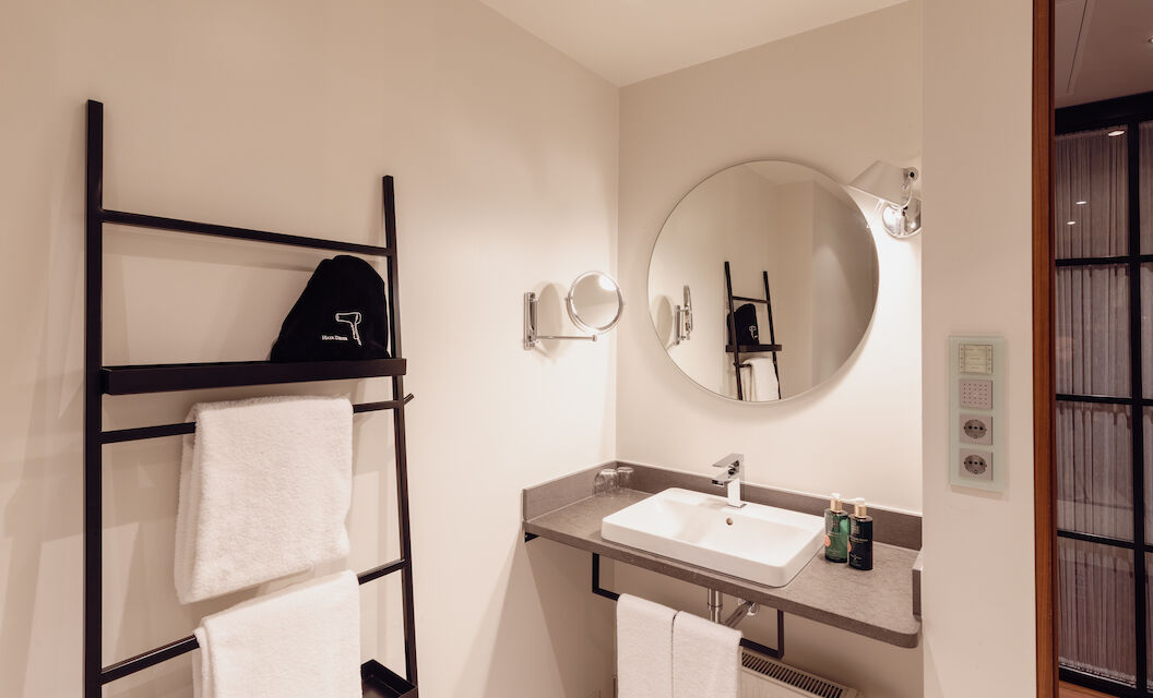 Das Badezimmer aus dem Gastwerk Hotel Hamburg M Loft Superior mit einem runden Spiegel.