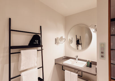 Das Badezimmer aus dem Gastwerk Hotel Hamburg M Loft Superior mit einem runden Spiegel.