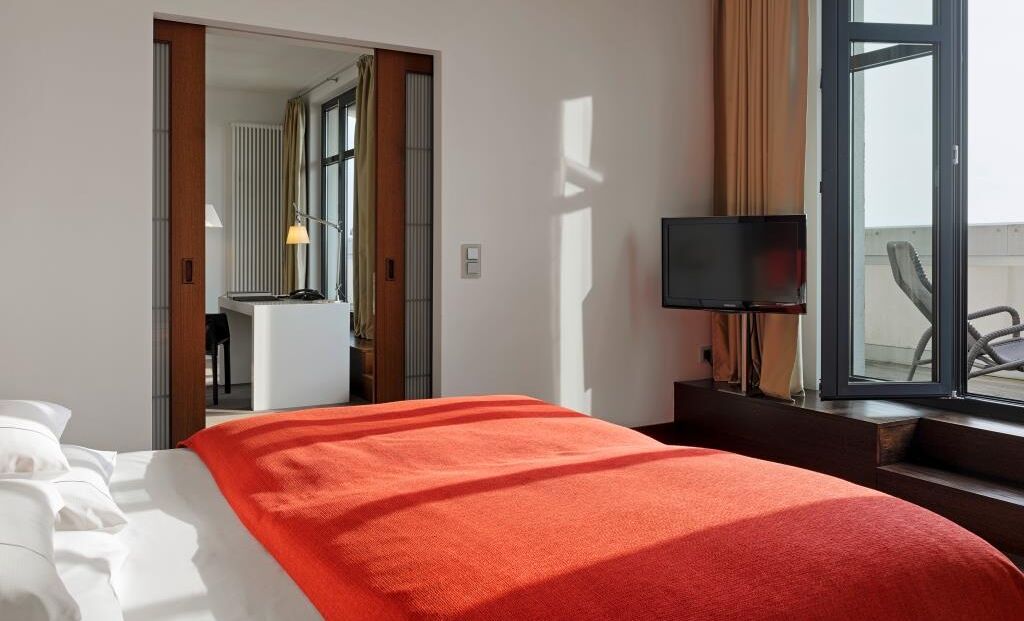 Schlafzimmer im XXL-Loft mit Bett, Fernseher und Terrasse mit Liegestühlen