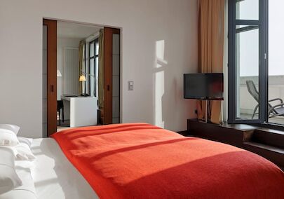 Schlafzimmer im XXL-Loft mit Bett, Fernseher und Terrasse mit Liegestühlen