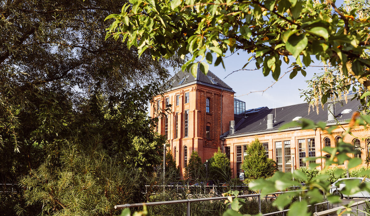 Gastwerk Hotel von Bäumen und Pflanzen eingerahmt, Außenansicht