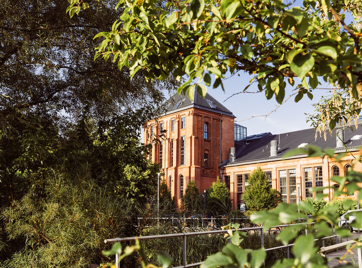 Gastwerk Hotel von Bäumen und Pflanzen eingerahmt, Außenansicht