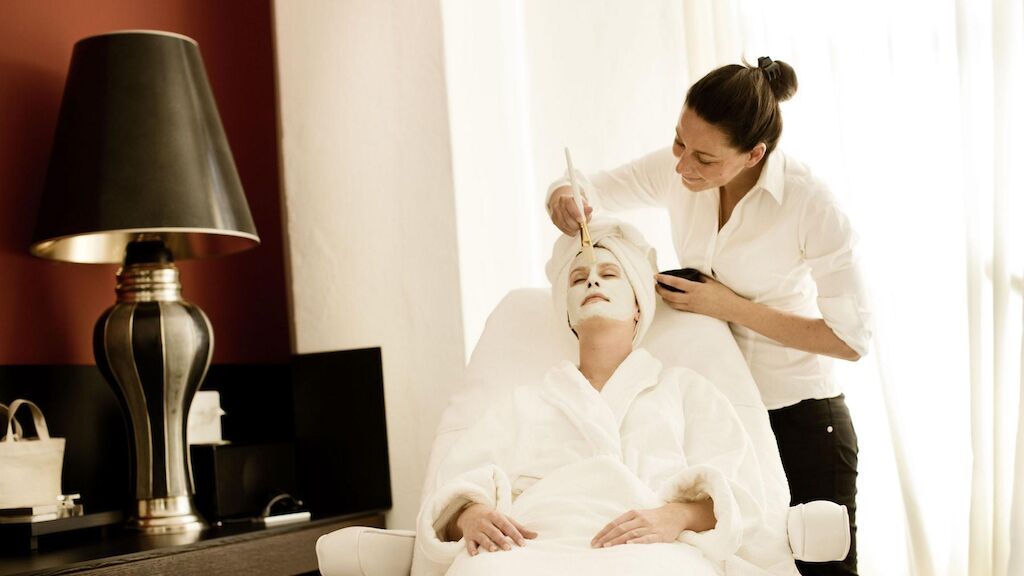 Professionelle Kosmetikerin trägt einer Frau im Spa eine Maske auf