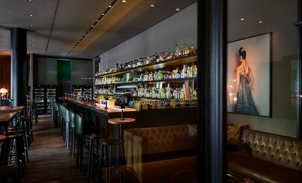 The George Hotel Hamburg Bar Dacaio 05 Long bar with fully stocked shelf of various spirits in view