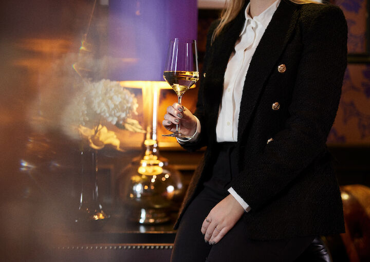 A person holding a glass of wine in the library at The George Hotel.