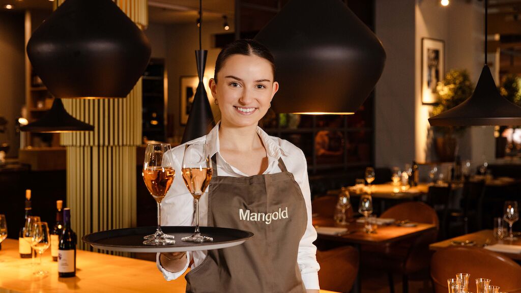 Servicemitarbeiterin serviert prickelnden Rosé-Champagner