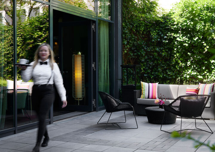 Colourful cushions on chairs, server brings drinks to guests