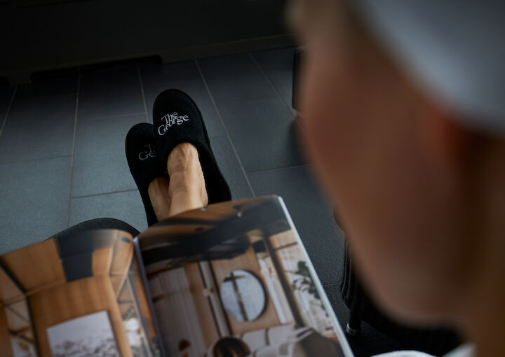 Shoulder shot of a woman in the sauna area of The George Hotel with slippers and a book