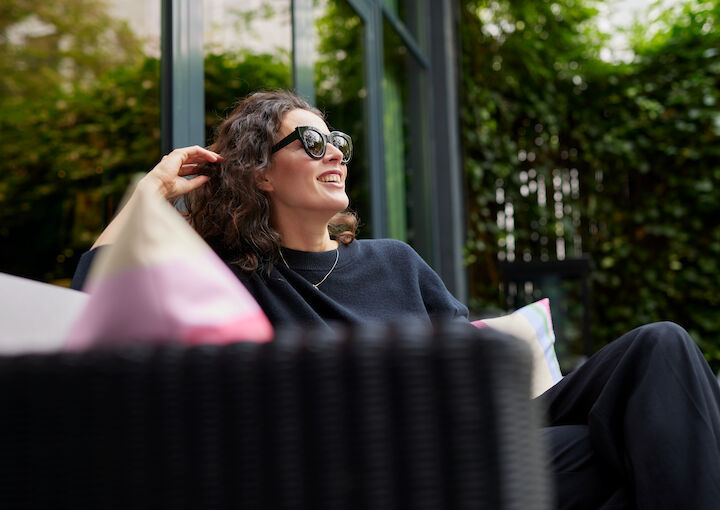 Smiling women sits on sofa in The George Garden