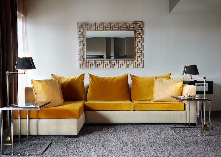 Large mustard sofa in front of mirror in hotel suite