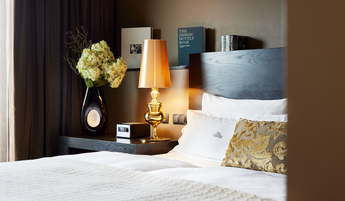 Seitenansicht des Doppelbett Kopfteils samt goldener Lampe sowie Büchern in Hintergrund