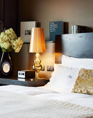 Seitenansicht des Doppelbett Kopfteils samt goldener Lampe sowie Büchern in Hintergrund