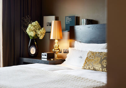 Side view of headboard with golden lamp and books in the background