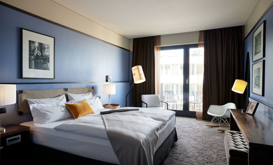 Double bed with gray bedspread and mustard cushion in the M-Room