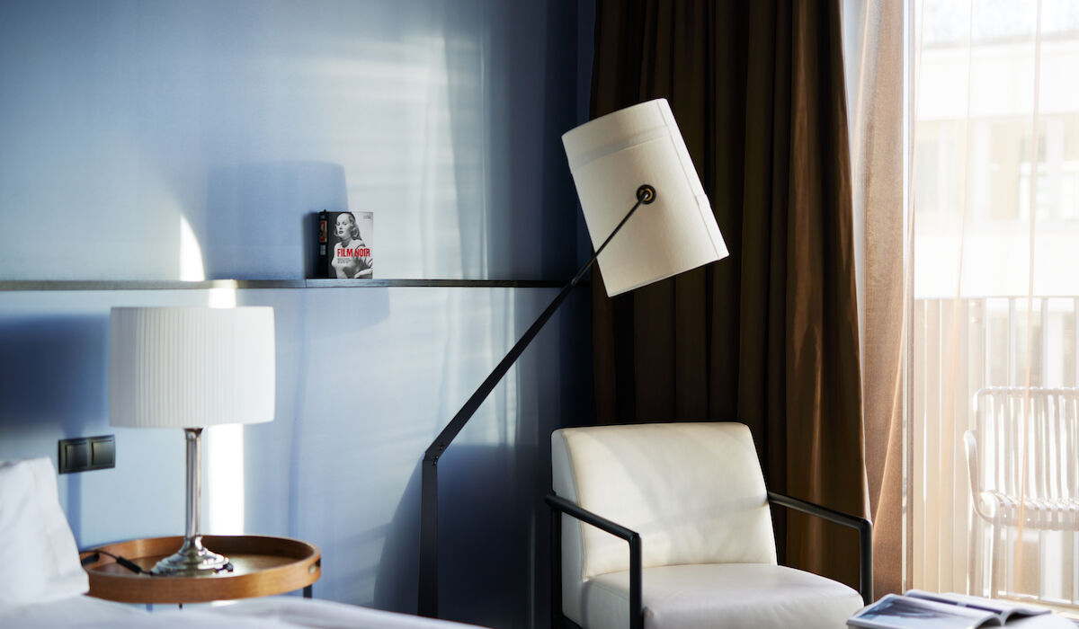 Weißer Sessel samt Stehlampe vor blauer Wand im M-Room