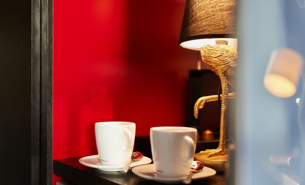 Two coffee cups on a shelf, flamingo lamp in the background