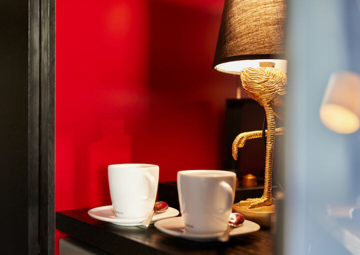 Two coffee cups on a shelf, flamingo lamp in the background