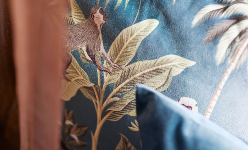 Close-up of a cushion featuring plants and monkeys