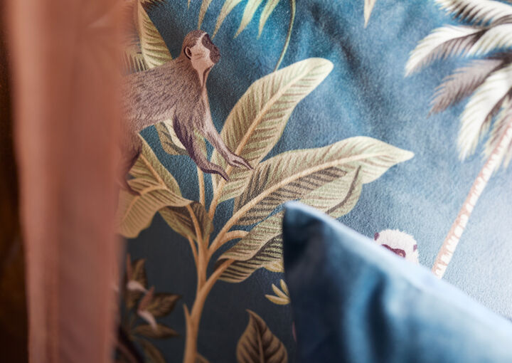 Close-up of a cushion featuring plants and monkeys