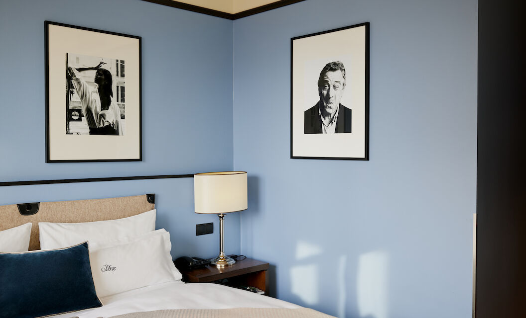 Blue wall behind double bed with a man's photo on it