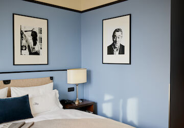 Blue wall behind double bed with a man's photo on it