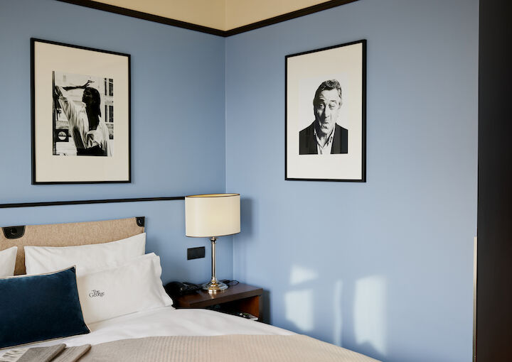 Blue wall behind double bed with a man's photo on it