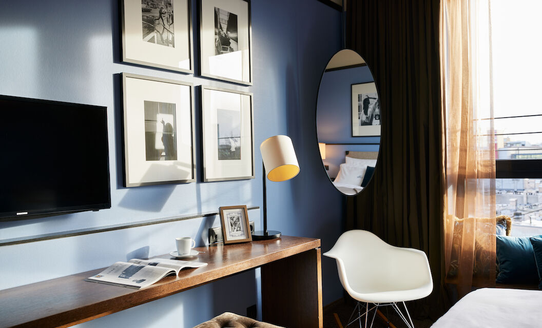 Room corner with wall art, narrow table, and Eames armchair