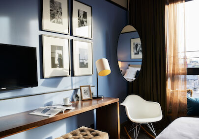 Room corner with wall art, narrow table, and Eames armchair