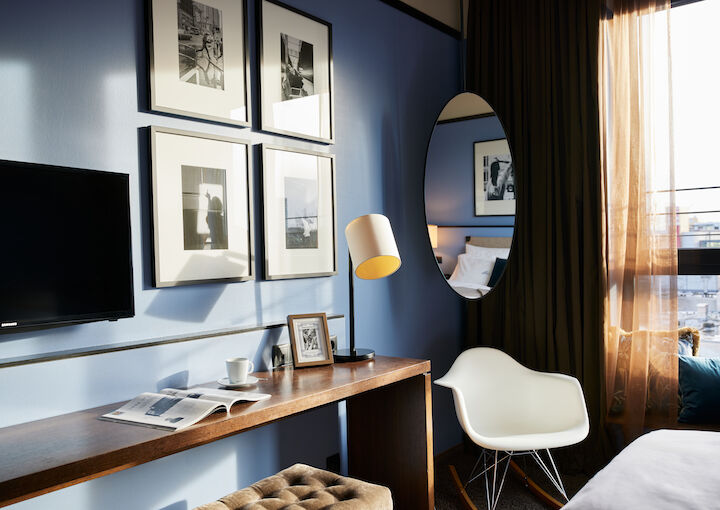 Room corner with wall art, narrow table, and Eames armchair