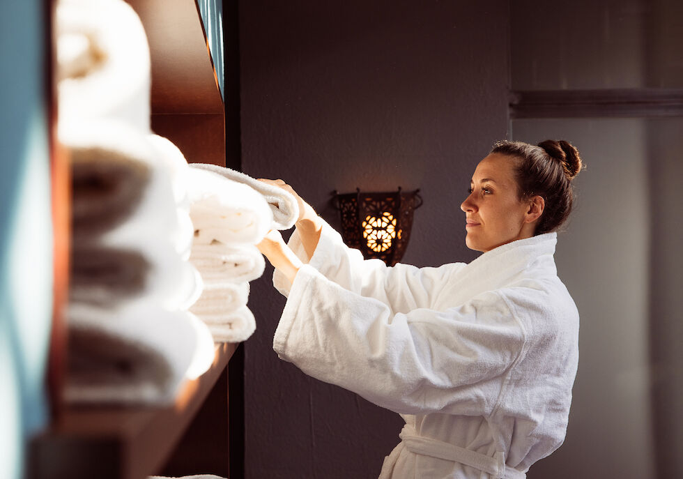 Frau nimmt ein Handtuch aus dem Regal im Cosy Spa