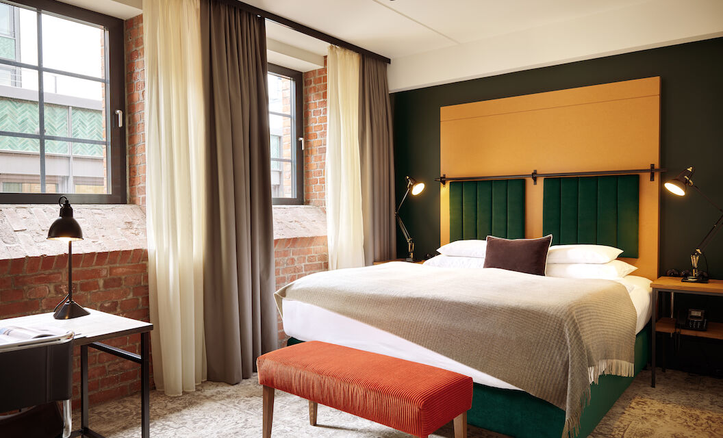 Doppelbett im S-Loft mit dunkelroter Sitzbank davor.