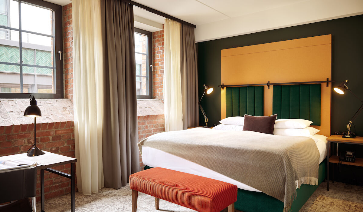 Gastwerk Hotel Hamburg Zimmer S Loft 01 Doppelbett im S-Loft mit dunkelroter Sitzbank davor.