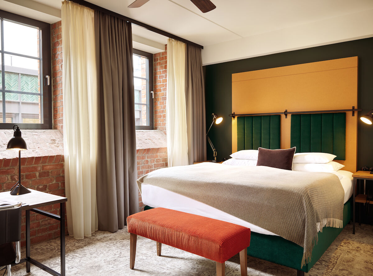 Doppelbett im S-Loft mit dunkelroter Sitzbank davor.