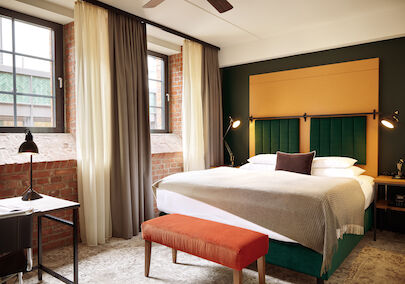Doppelbett im S-Loft mit dunkelroter Sitzbank davor.