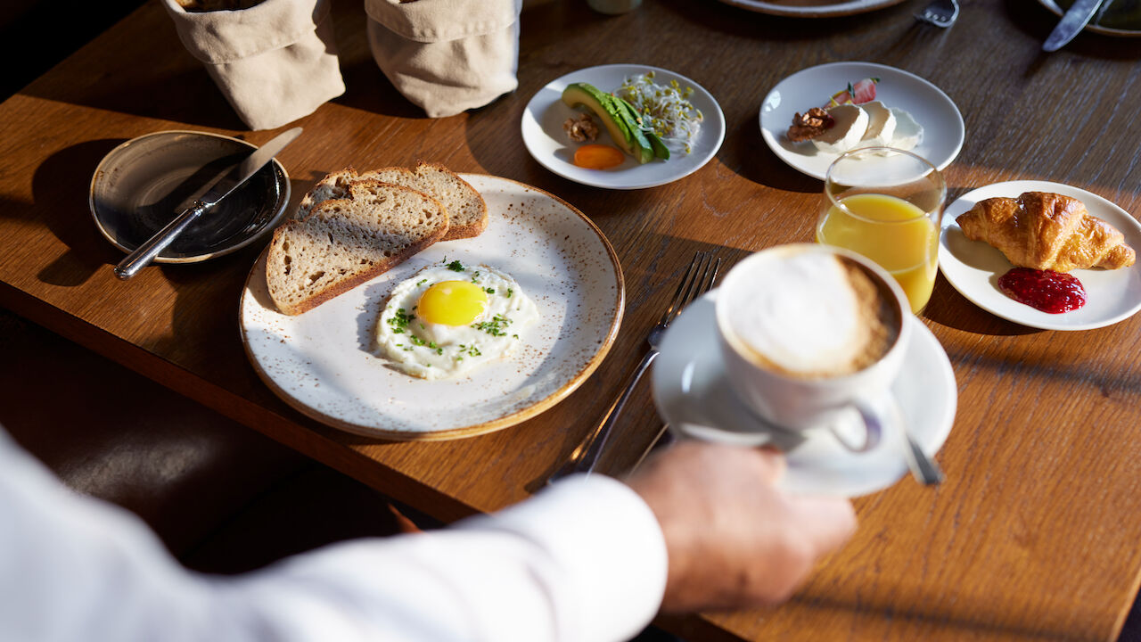 Frühstück mit Spiegelei, Avocado, Käse und einem Cappuccino