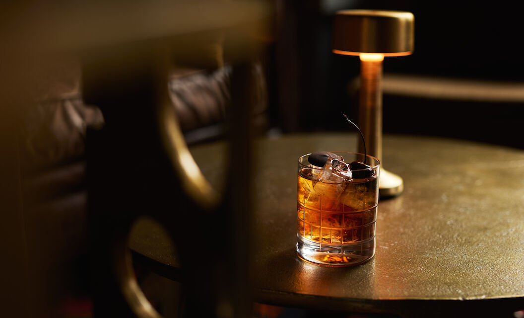 Drink im Tumblerglas auf goldenem Couchtisch