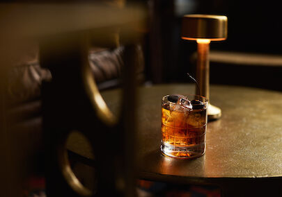 Drink im Tumblerglas auf goldenem Couchtisch