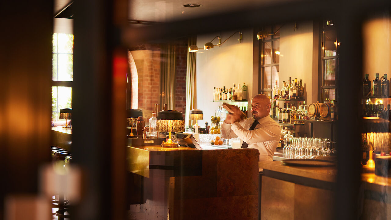 Barkeeper mixt hinter dem Tresen der Bar Mangold einen Drink.